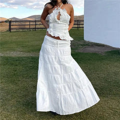 Woman wearing a white ruffled dress standing outdoors with a scenic background