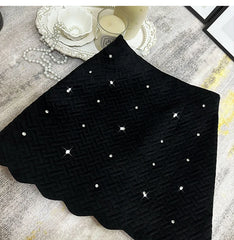 Black textured fabric with white polka dots on a gray surface