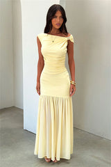 Woman wearing a light yellow off-shoulder dress against a plain background