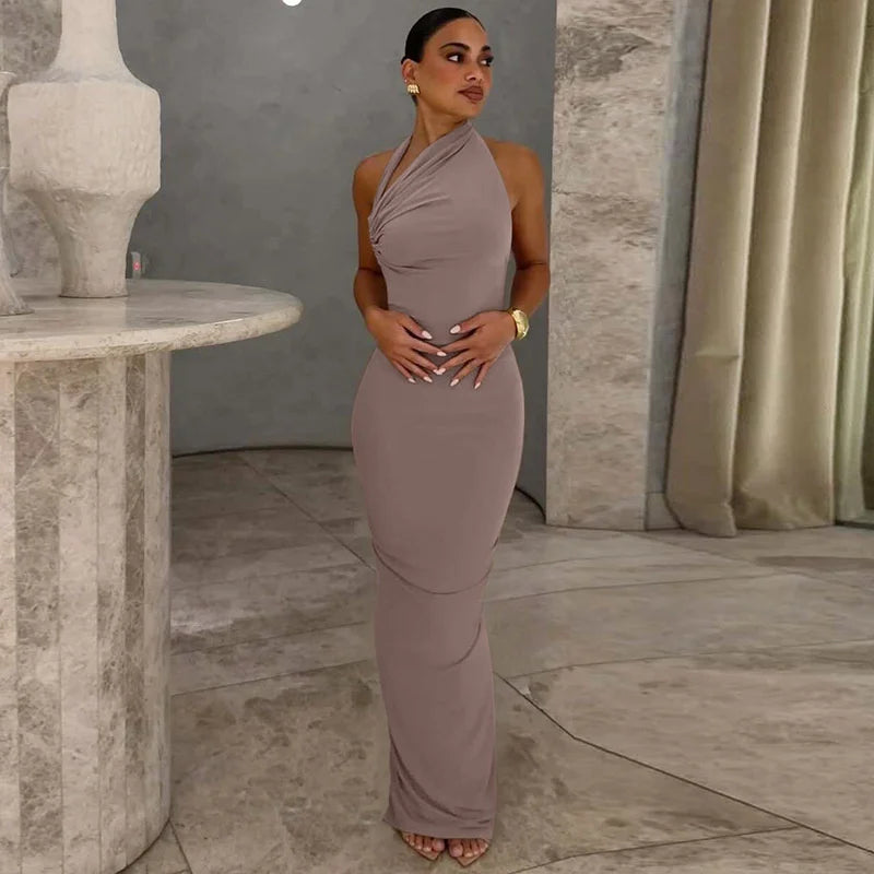 Woman in a brown halter neck gown standing in an elegant interior setting.
