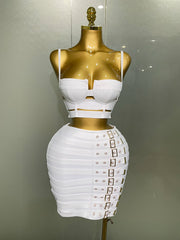 White dress with gold accents on a mannequin against a neutral background