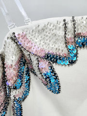Close-up of a decorative dress with multicoloured sequins on a white background