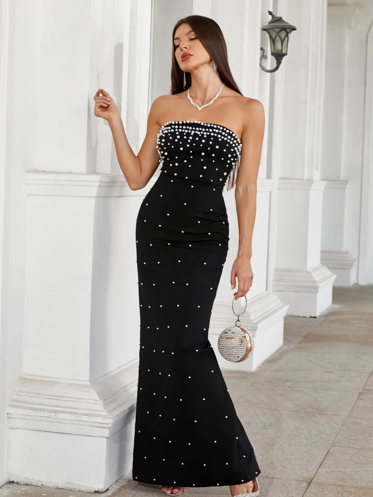 Woman wearing a black strapless dress with white embellishments in an elegant setting.