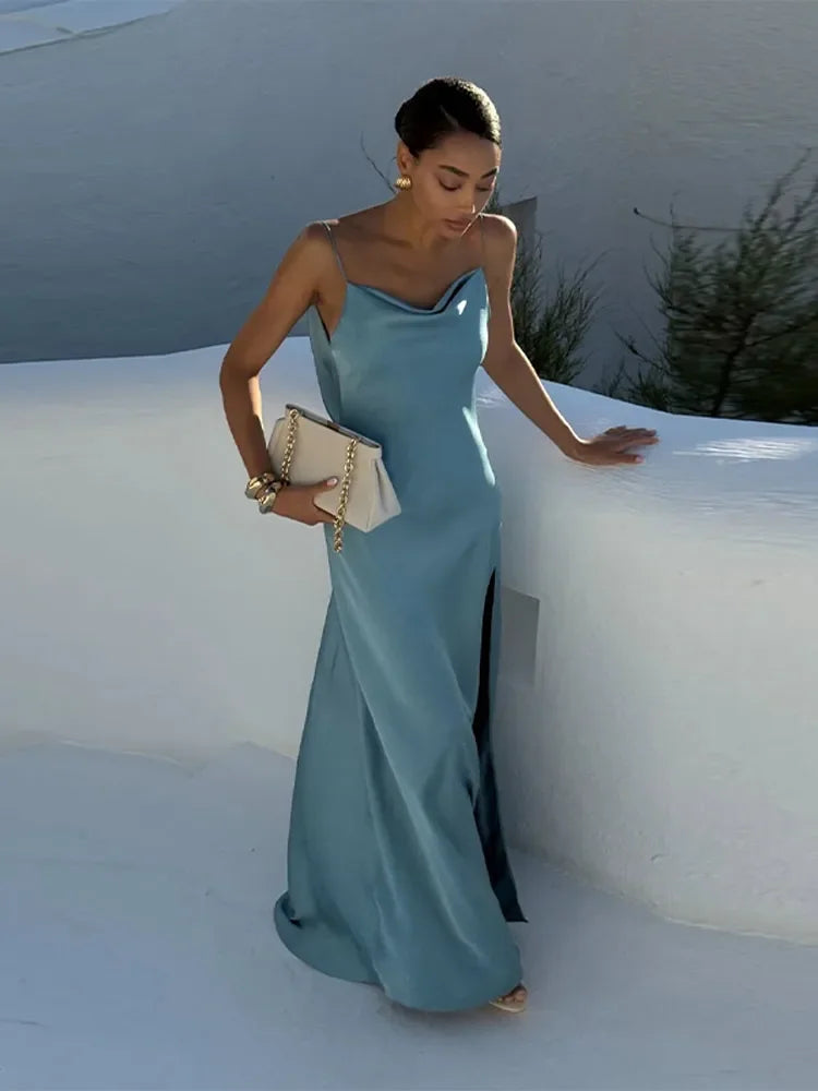 Woman in a light blue evening gown standing against a white wall.