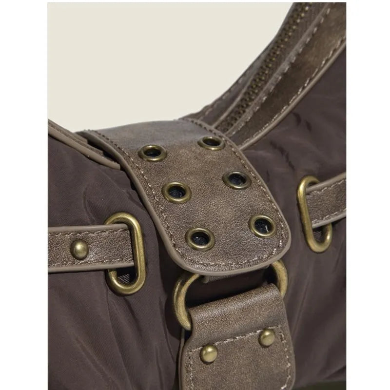 Close-up of a brown leather bag with brass hardware on a beige background