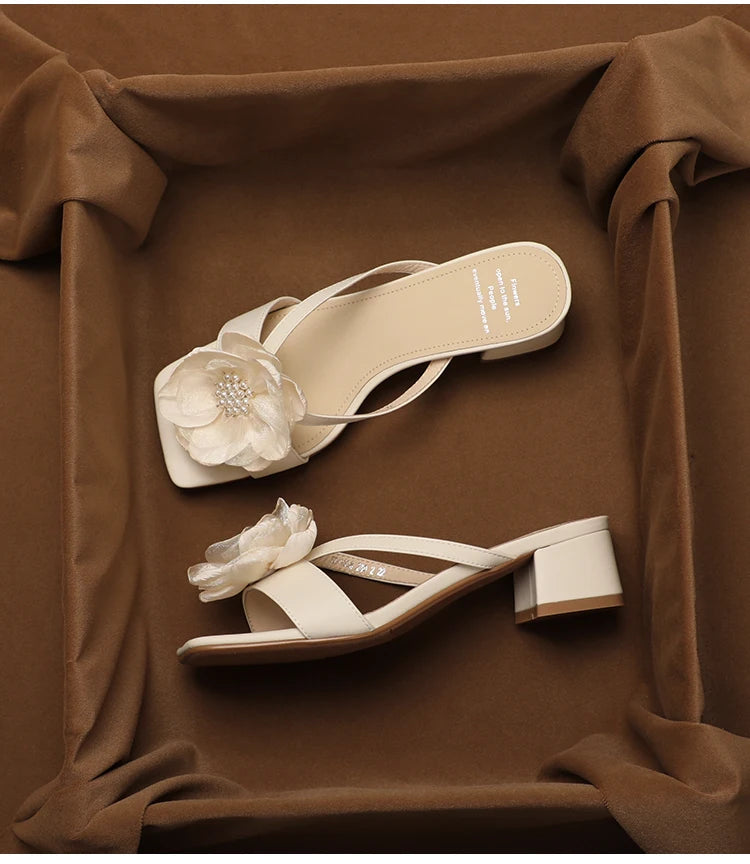 White sandals with floral details on a brown fabric background