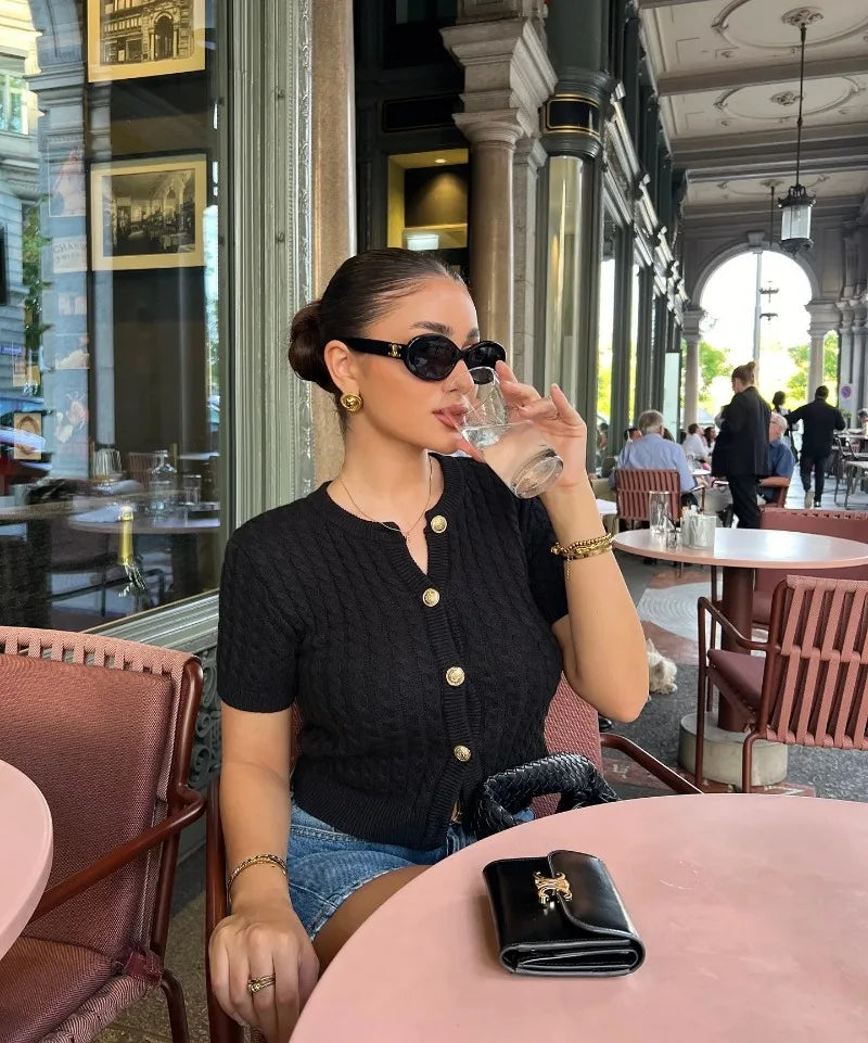 Woman sitting at a table in an elegant restaurant, holding a glass of water.