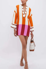 Model posing with a handbag in a striped v-neck mini dress with bell sleeves