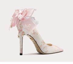 Delicate high-heeled shoe with floral design and bow on a white background