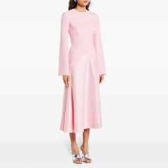 Model in a pink patchwork A-line midi dress with long sleeves and round neckline, studio background