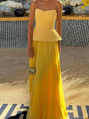 Woman wearing a yellow strapless top and pleated skirt with a blurred background