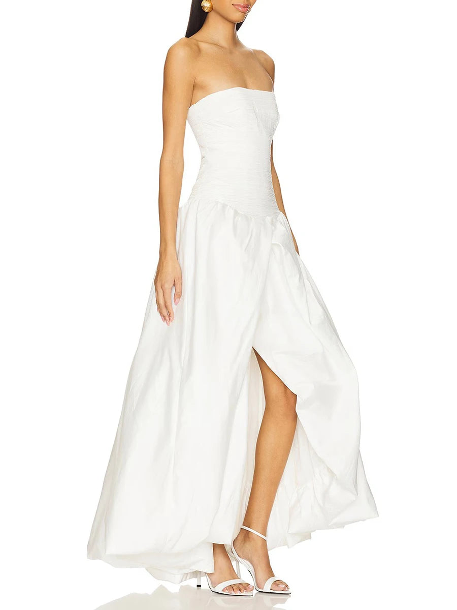 Woman wearing a strapless white dress with a slit on a white background