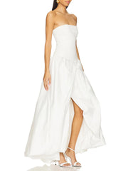 Woman wearing a strapless white dress with a slit on a white background