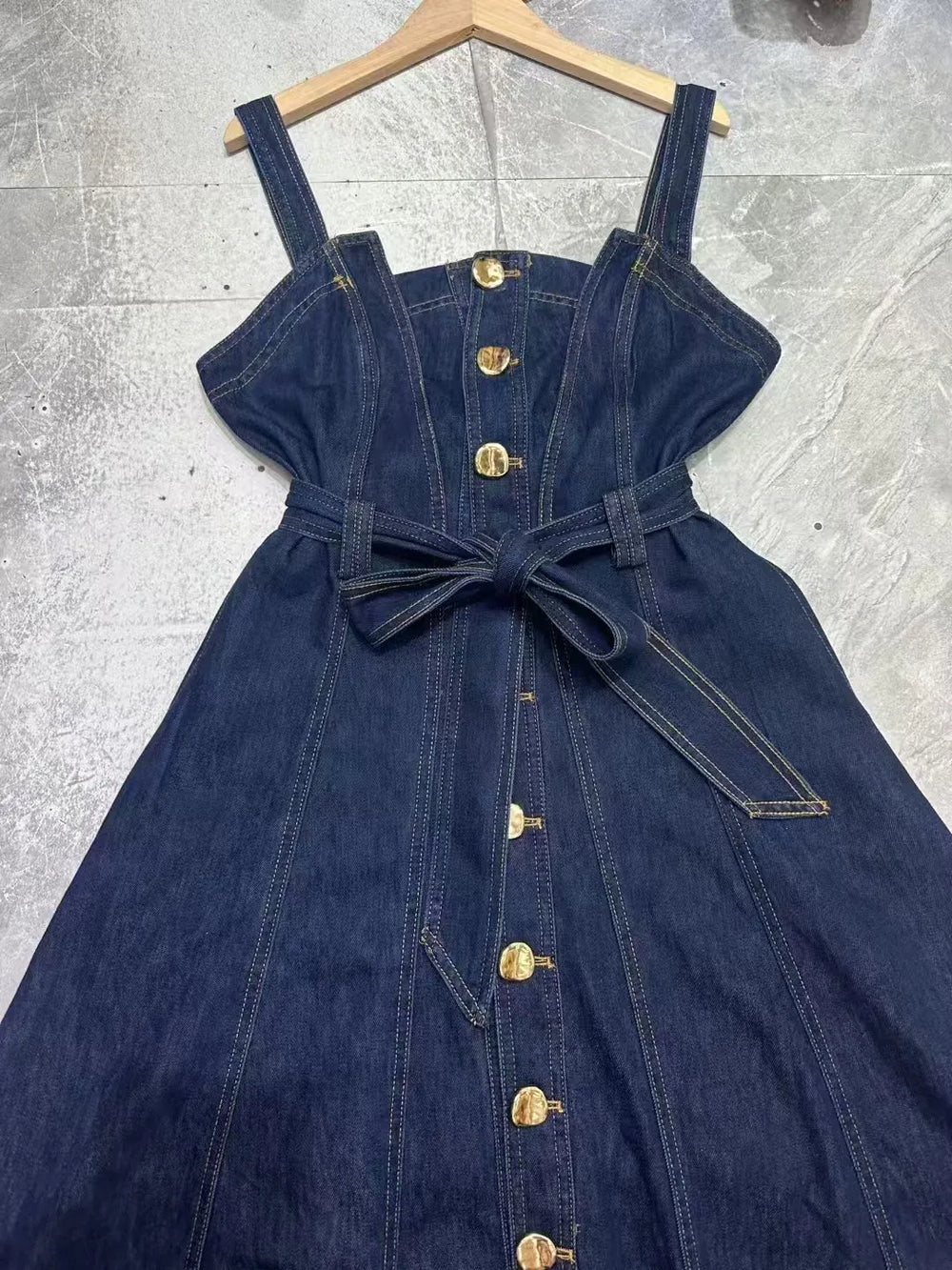 Close-up of denim midi dress bodice with button front and belt