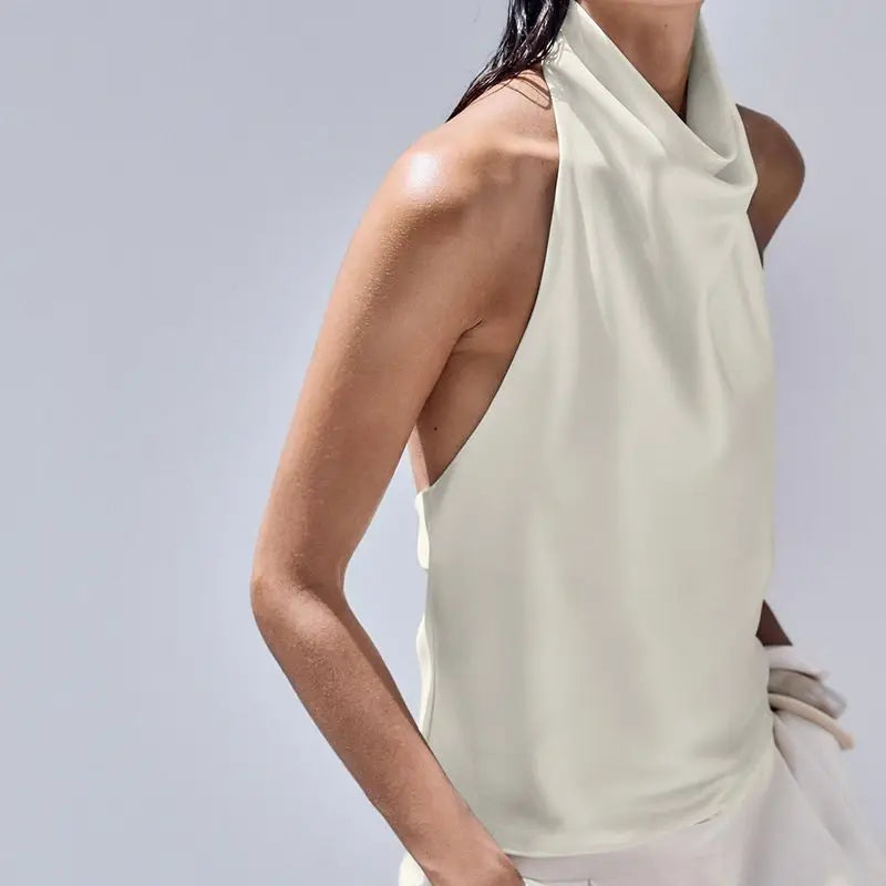 Woman wearing a light-colored sleeveless top against a gray background