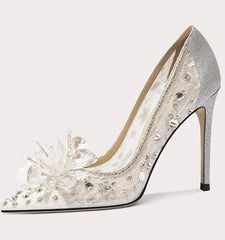 Silver high-heeled shoe with floral design on a light gray background