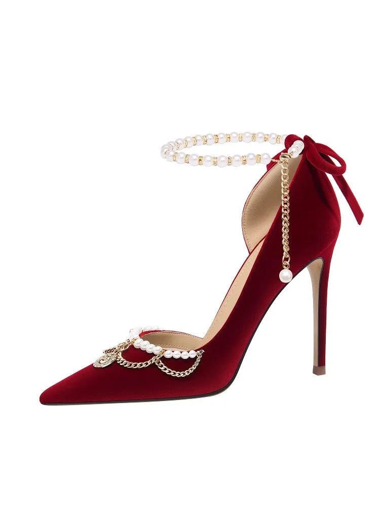 Red high-heeled shoe with pearl and chain detail on a white background