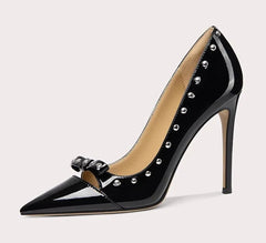 Black high-heeled shoe with studded details on a light gray background