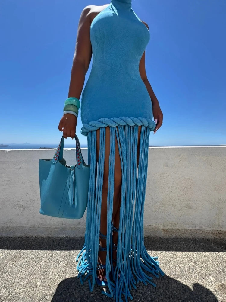 Person wearing a blue fringe dress holding a matching blue handbag against a clear blue sky.