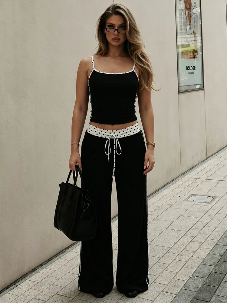 Model wearing black camisole top and wide-leg pants set with polka dot trim