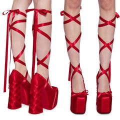 Red high-heeled shoes with ribbon detailing on a white background