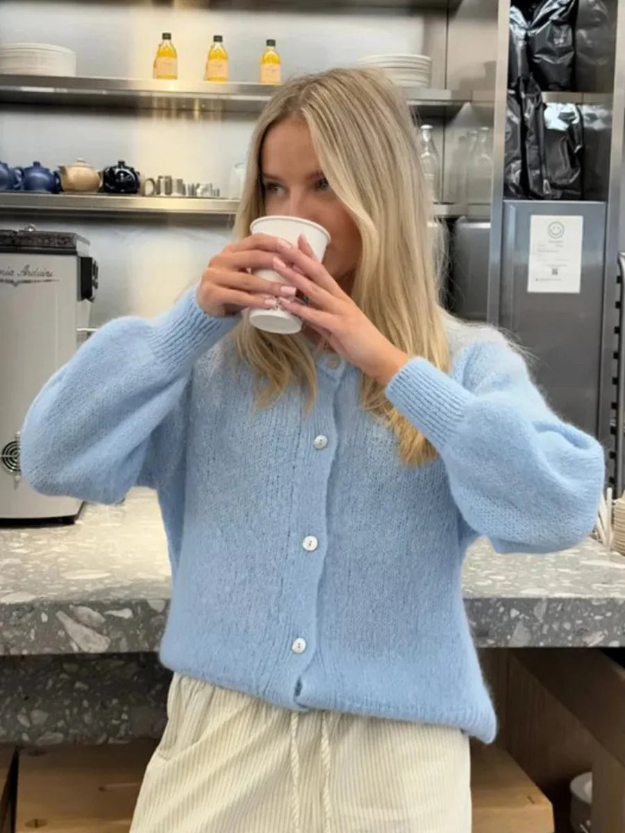 Person wearing a light blue sweater in a kitchen setting