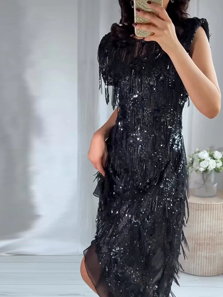Person wearing a black sequin dress with feather details, taking a mirror selfie.