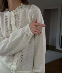 Person wearing a white lace-trimmed sweater in an indoor setting