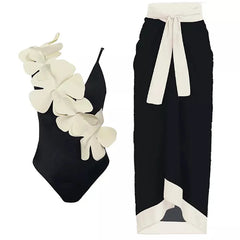 Black one-piece swimsuit with white floral embellishment and a black wrap skirt with white trim.