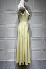 Mannequin wearing a light yellow dress against a white paneled wall.