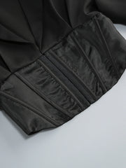 Close-up of a black garment with pleated details on a light gray background