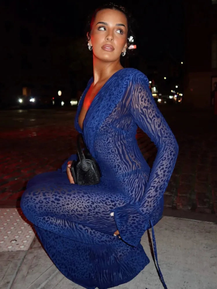 Woman in a blue lace dress sitting outdoors at night.