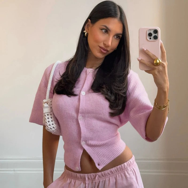 Woman in a pink outfit taking a mirror selfie with a phone.