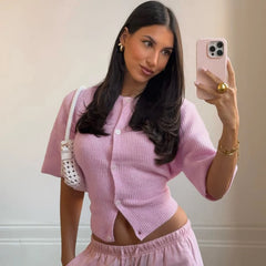 Woman in a pink outfit taking a mirror selfie with a phone.