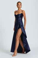 Woman wearing a navy blue evening gown with a slit on a white background