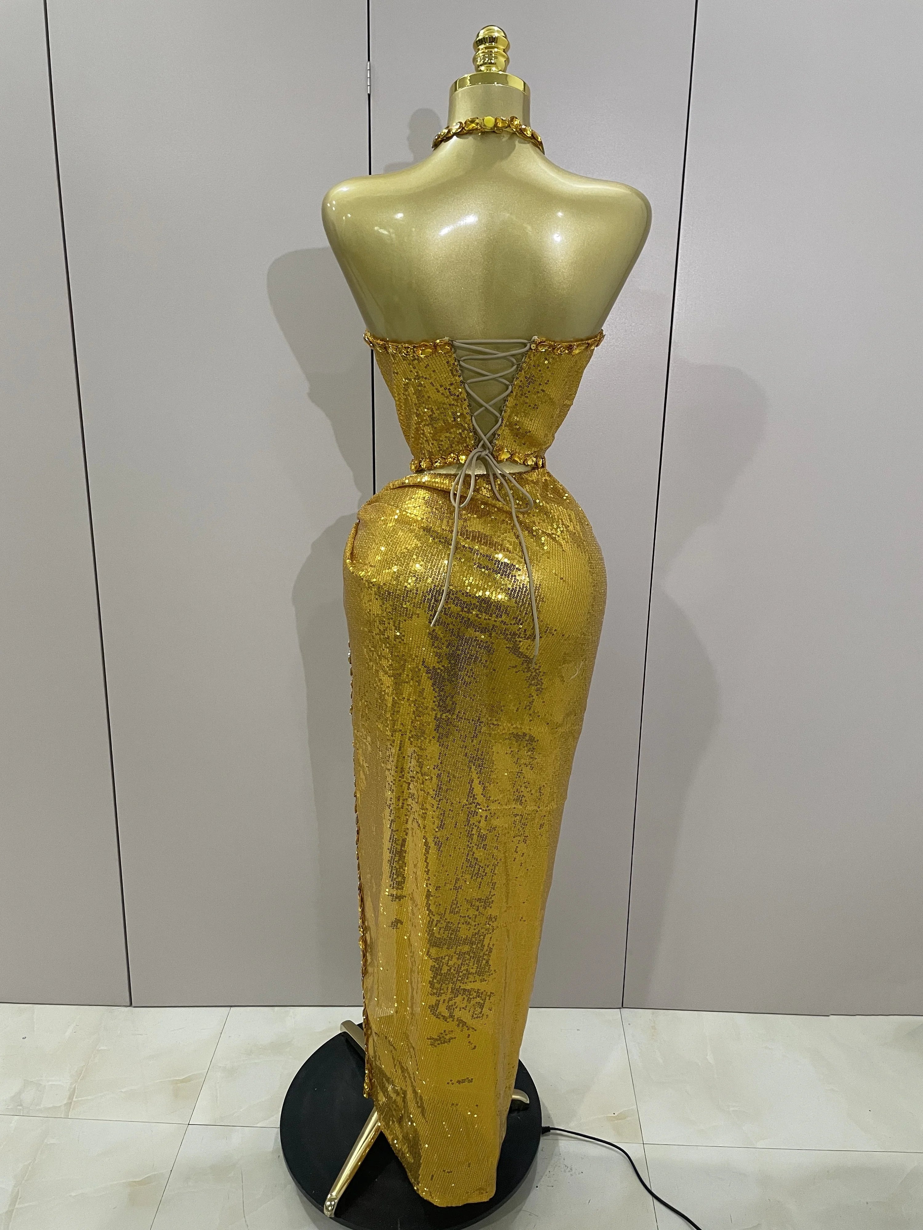 Gold evening gown on a mannequin against a plain background