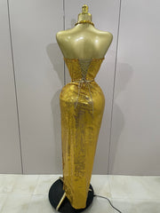 Gold evening gown on a mannequin against a plain background