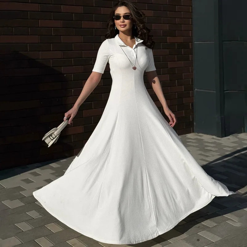Woman in a white dress standing against a brick wall.