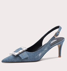 Blue denim high-heeled shoe with a decorative buckle on a light gray background