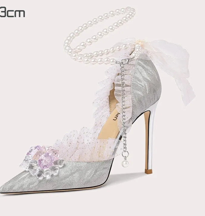 High-heeled shoe with decorative flower and chain on a white background