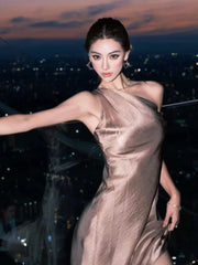 Close-up of a woman in a one-shoulder satin maxi dress at an evening event