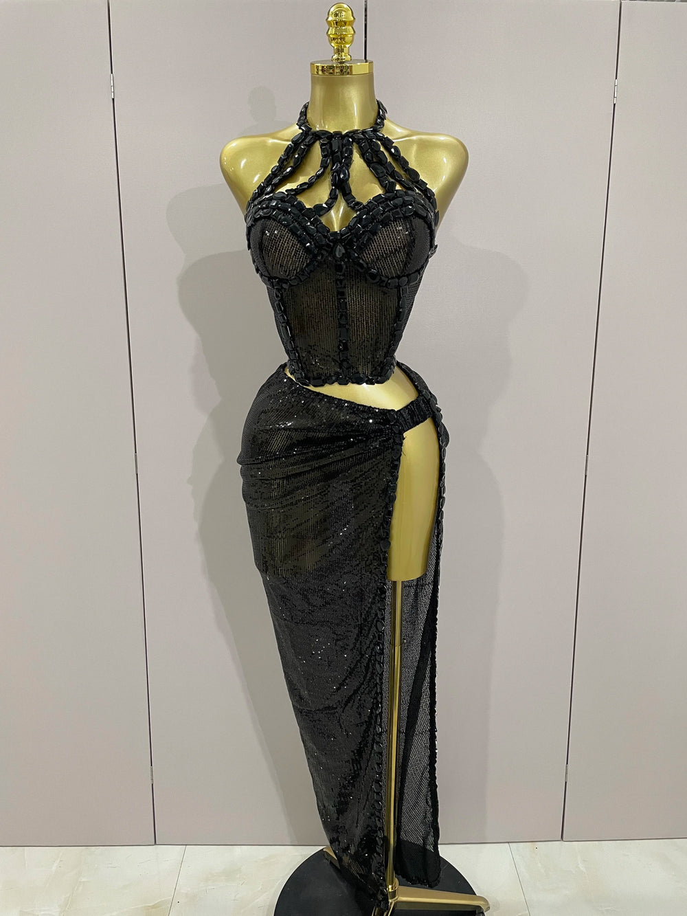 Black beaded evening gown on a mannequin against a plain background