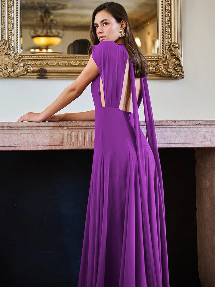 Woman in a purple evening gown standing in an elegant interior setting.