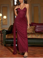 Woman wearing a burgundy evening gown in an elegant room with a sofa and lamp.