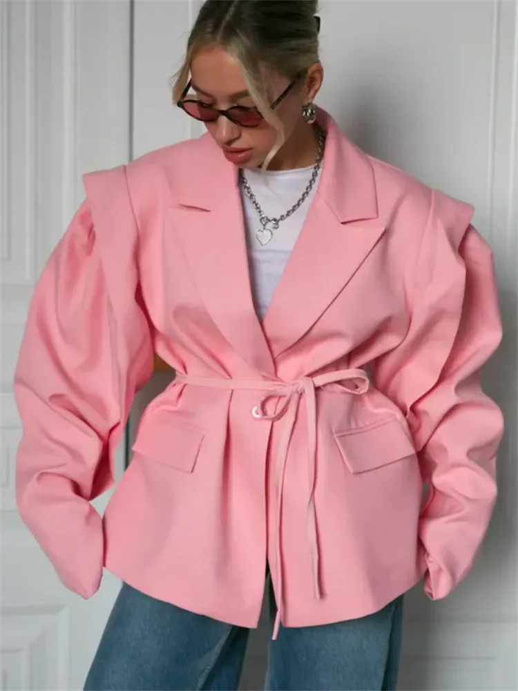 Person wearing a pink coat against a white wall