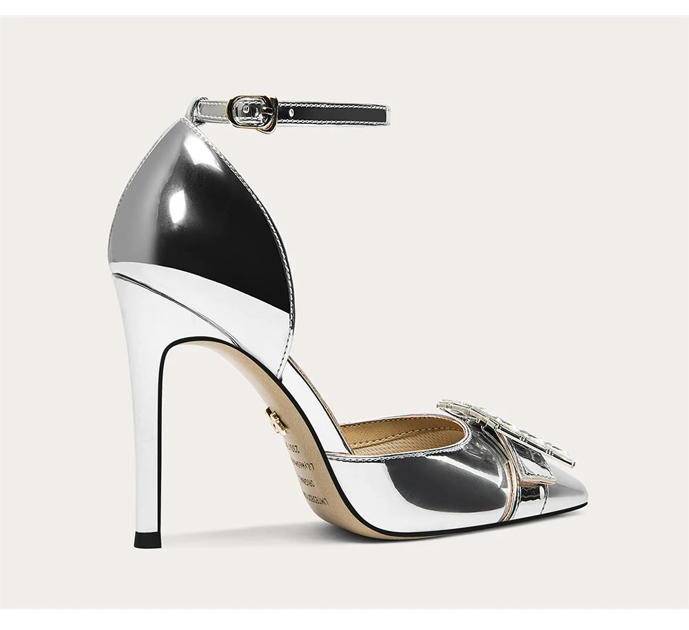 Silver high-heeled shoe with a strap on a light gray background