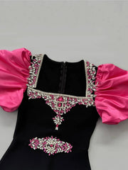 Black dress with pink sleeves and embellishments on a gray background