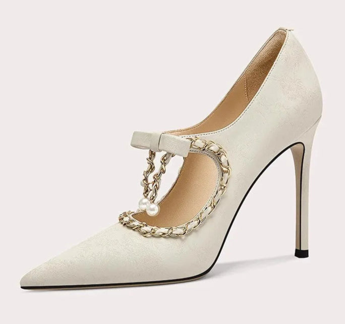 White high-heeled shoe with gold chain detail on a white background