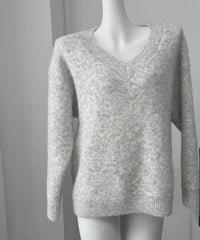 Gray sweater on a mannequin with a framed quote 'EVERYTHING WILL BE FINE' in the background.