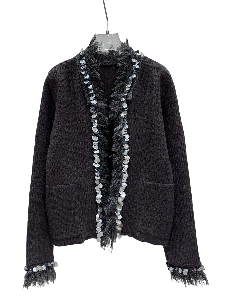 Black textured sweater with decorative fringes on a white background